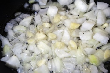 Little chopped onions sweating in a cooking pot - 210983499