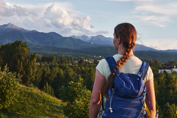 Naklejka premium Young tourist woman looking at the peaks of the Almaty mountain. Almaty, Kazakhstan