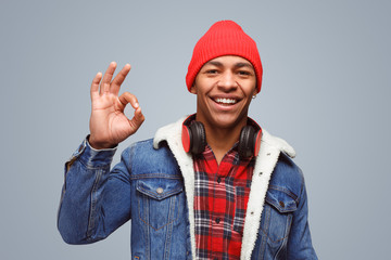 Handsome guy showing OK gesture on gray