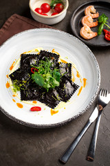 cooked black ravioli, served on a white plate
