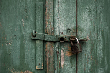 Fragment of old green wooden door with padlock. Vintage timber texture background.