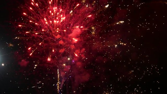 Sparks of fireworks scatter over the night sky in the smoke
