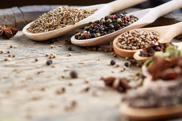 Colourful aromatic various spices for cooking on old wooden board, close-up, flat lay, selective focus, vertical.