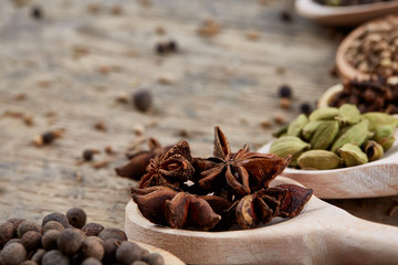 Colourful aromatic various spices for cooking on old wooden board, close-up, flat lay, selective focus, vertical.