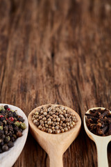 Row of wooden spoons with spices on vintage background, close-up, selective focus, vertical.