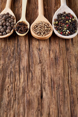 Row of wooden spoons with spices on vintage background, close-up, selective focus, vertical.