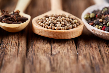 Row of wooden spoons with spices on vintage background, close-up, selective focus, vertical.