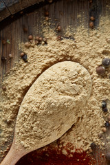 Top view of a wooden spoons full of paprica and black pepper on wooden barrel background, selective focus.