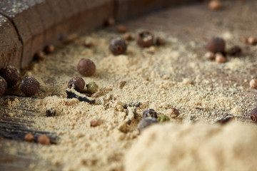 Top view of a wooden spoons full of paprica and black pepper on wooden barrel background, selective focus.