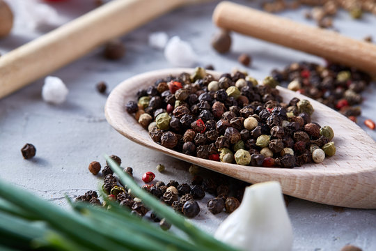 Composition with aromatic peppercorn in the wooden spoons on the white background, flat lay, close-up, selective focus.