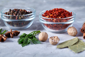 Three glass bowls with spices arranged in rows on white textured background, view from above.