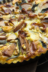 vegetarische Steinpilz-Tarte mit Pinienkernen in Backform auf einem Gitter