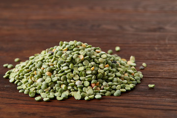 Pile of green peas on rustic wooden background, close-up, top view, selective focus.