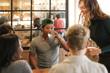 Diverse group of friends ordering food from a bistro waitress
