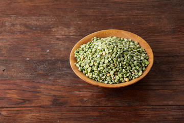 Nutritious green peas in a bowl and plate on rustic wooden background, close-up, top view, selective focus.