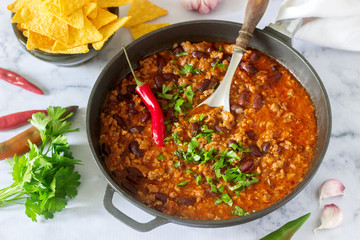 Mexican and American food Chili con carne served with nachos, pepper and herbs.