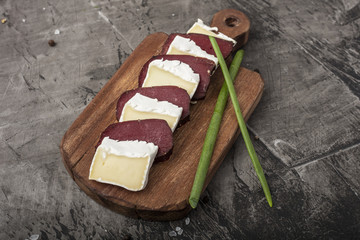 Hardened meat and soft cheese with white mold. Slices of cheese and hardened meat on a wooden board...