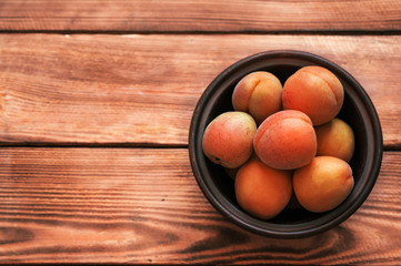 Bowl of raw apricots on a rustic wooden background  with a copy space for text
