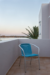 Blue chair on the terrace overlooking the sea in the sunset