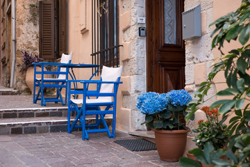 Resting place with blue chairs on the narrow street in Greece
