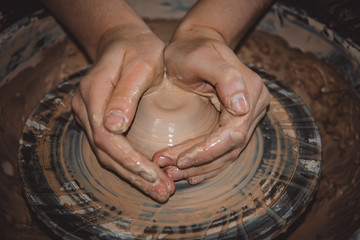 Creating ceramic products of white clay close-up. The sculptor in workshop makes clay jug closeup. Master crock. Twisted potter's wheel. Art, creativity. Cultural traditions. Handmade. Craft.