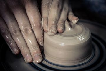 Creating ceramic products of white clay close-up. The sculptor in workshop makes clay jug closeup. Master crock. Twisted potter's wheel. Art creativity Cultural tradition Handmade Craft Master's Hands