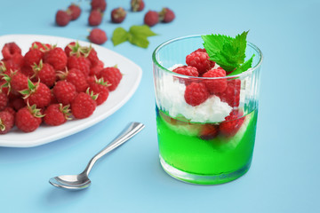 Refreshing summer dessert - gelatin with berries and whipped cream, on a blue background