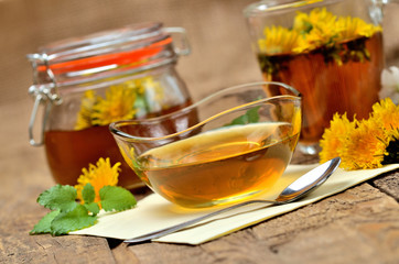 Dandelion honey, herbal tea, full jar of honey, spring flower, fresh mint leaves, spoon and dandelion head around - healthy snack