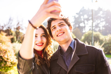 Young beautiful couple in love using smart phone together outdoor in the city - interaction, love, technology concept