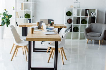 interior of modern business office with laptops on table, chairs, shelves and furniture