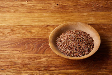 Close-up buckwheat in a round wooden plate over homespun tablecloth, top view, selective focus.
