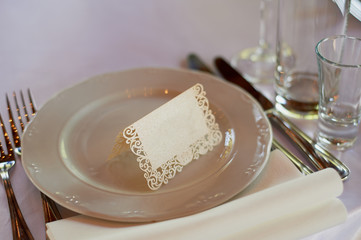 Classic table setting. Appliances, glasses, white tablecloth and plate, a card with a name on the plate