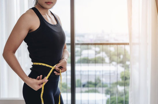 An asian woman use their own waist measurement straps. To control the size and shape of yourself after exercise.
