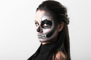 Studio portrait of beauty brunette woman wearing black clothes with scary greasepaint on face standing on white background