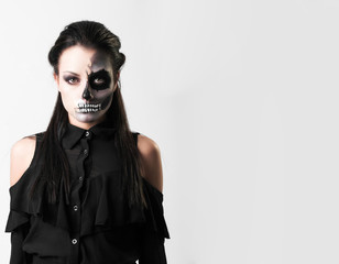 Studio portrait of beauty brunette woman wearing black clothes with scary greasepaint on face standing on white background