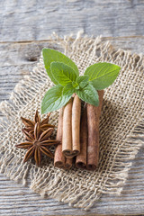 Cinnamon sticks and anise stars with mint on wooden background. Fragrant Oriental spice