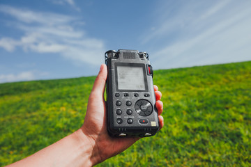 portable audio recorder in hand field recording ambient sounds of nature
