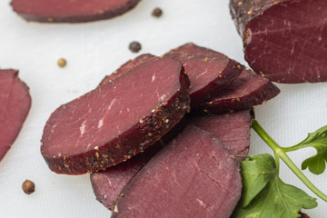 Dried meat on a cutting board with greens