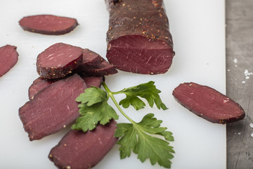 Dried meat on a cutting board with greens