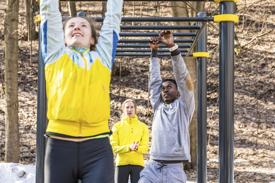 Friends exercising at monkey bars in a park