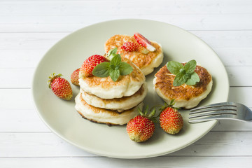 Curd pancakes with strawberries and mint on a plate