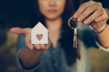 Woman hand holding house key for new owner. Property home sale.