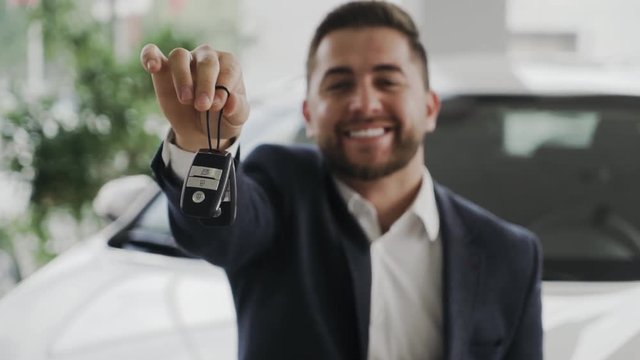 Happy young professional is showing the keys of his new car. Looking representive.