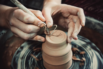 Master removes the top layer of clay on pot with a special tool. Create clay vessel. Modeling white-clay, shaping vessel. Caucasian man making vessel. Clay in circle.