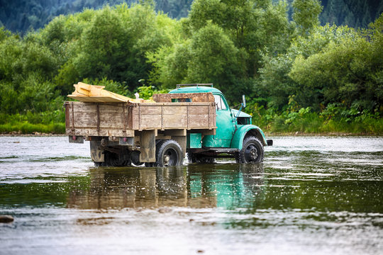 old truck transports cargo wade across the river