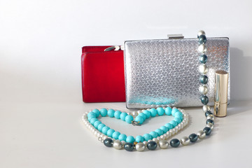 purse, handbag and bijouterie with lipstick on a light background