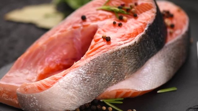 Salmon. Raw trout fish steak with herbs and lemon on slate. Cooking, seafood. Healthy eating concept. Slow motion 4K UHD video 3840x2160