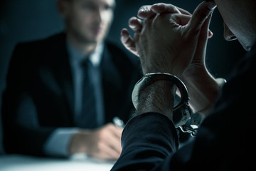 Criminal man with handcuffs in interrogation room - obrazy, fototapety, plakaty