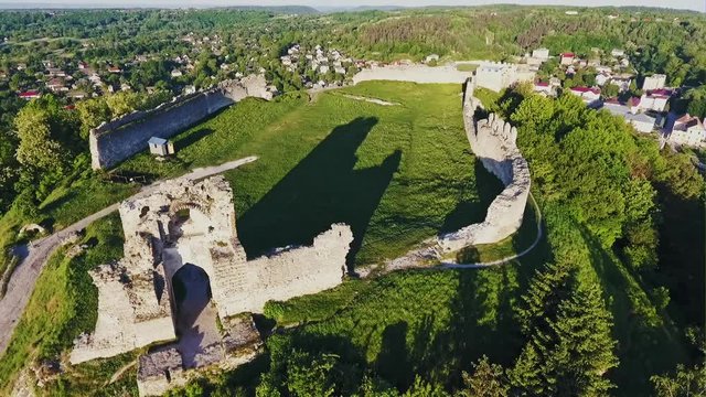 Aerial view of beautiful old ruined merlon battlement with remnants of gate of fortress placed on high Bona hill covered by green grass and trees with town around on summer day in Kremenets in Western