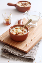 Baked Coconut Cream with Apricots and Crumble, in a little pot, on wooden board, on white background. 


